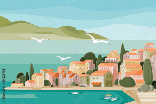 Mediterranean landscape with sea, mountains, beach and small houses with red roofs and seagulls flying over it all, photo