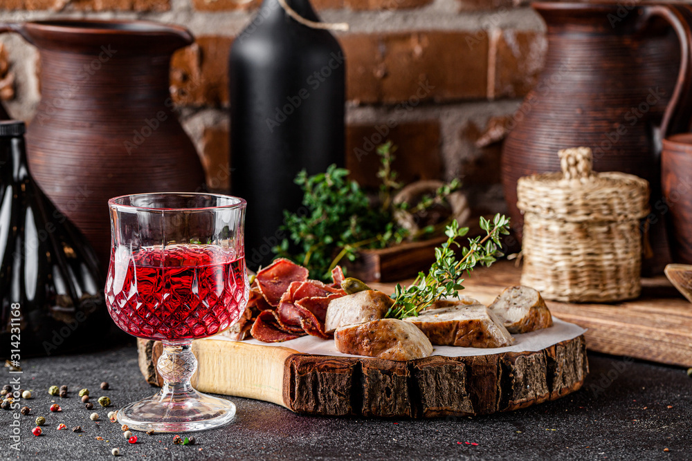 Georgian cuisine. Pomegranate ?hacha alcoholic drink with assorted different cured sausages and meat. Serving dishes in a Georgian restaurant. background image, copy space