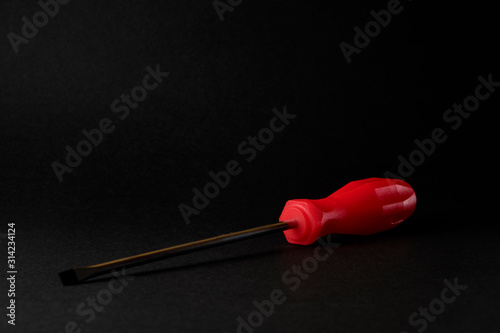 screwdriver with red handle on black background