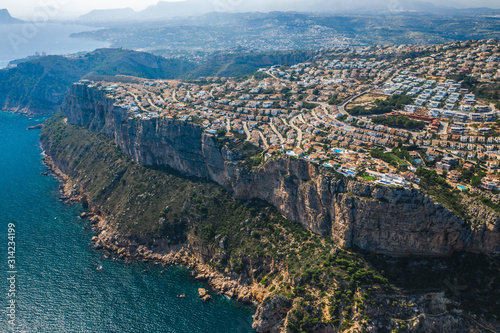 Top aerial view of Montecala village with colorful buildings, villas and pools on rock cliff el cim del sol, Alicante, Spain
