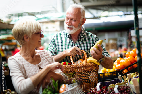 Senior family couple choosing bio food fruit and vegetable on the market during weekly shopping