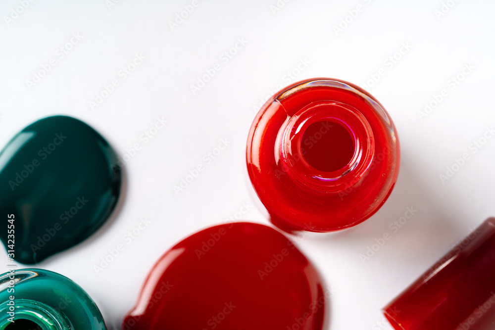 Nail polishes spilled out of bottles on white background Nail polishes spilled out of bottles on white background