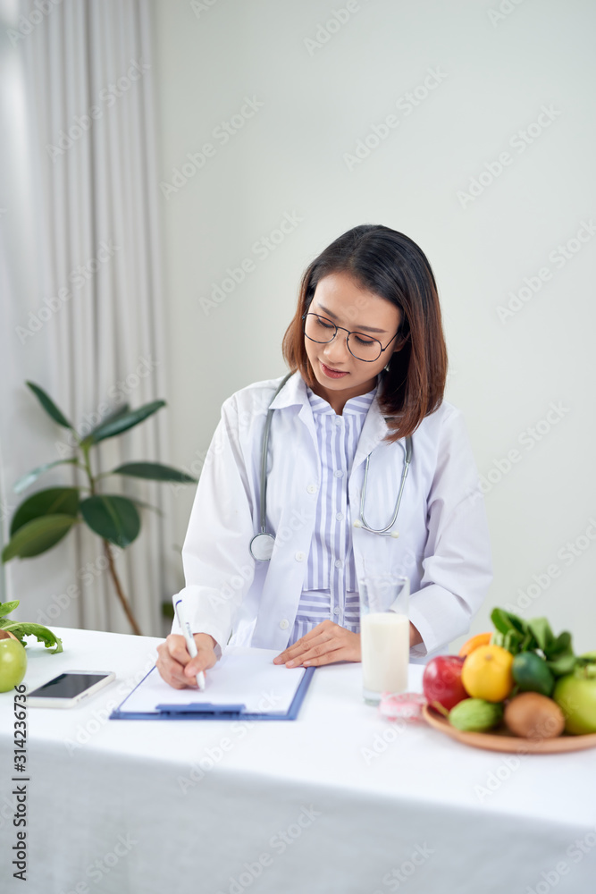 Asian Female nutritionist with fruits working at her desk. Health care and diet concept. Asian Female nutritionist with fruits working at her desk. Health care and diet concept.