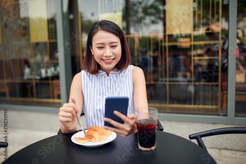 Portrait of beautiful young woman using smartphone while enjoying evening on outdoor coffee shop  copy space