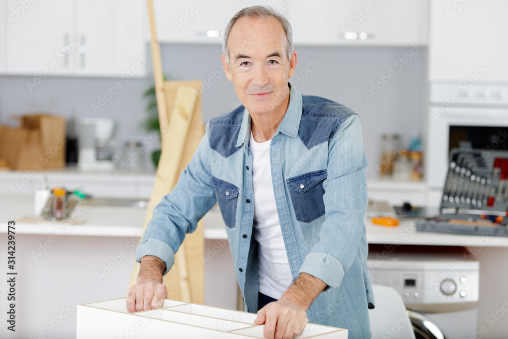 senior man assembling flat pack furniture senior man assembling flat pack furniture