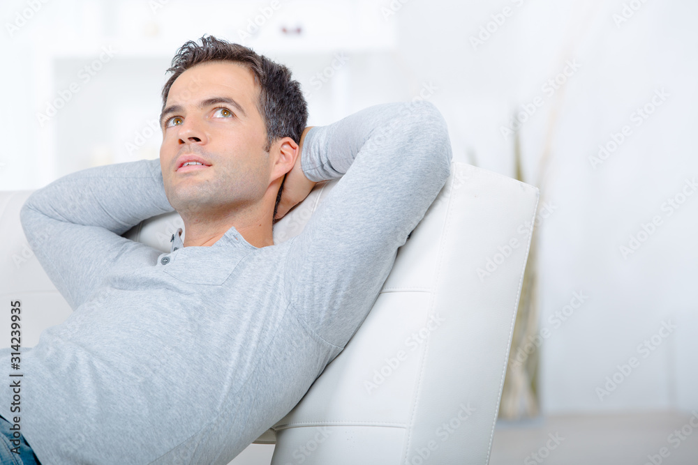 contemplative man layed on sofa arms behind head contemplative man layed on sofa arms behind head