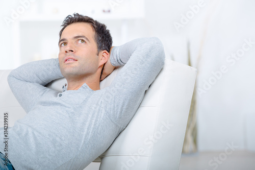 contemplative man layed on sofa arms behind head