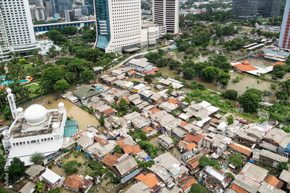 The flooded street in a poor residential district in the heart of Jakarta city in Indonesia capital city which show huge inequalities with modern towers surrounding it