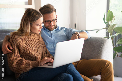 Young couple ordering online, looking in laptop	 photo