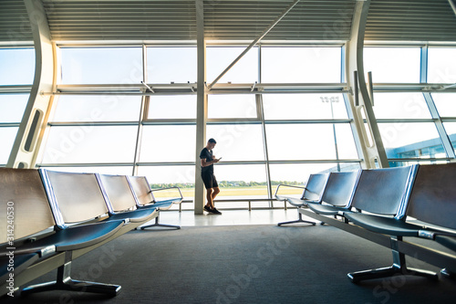 Young man waiting for departure at the airport while using his phone