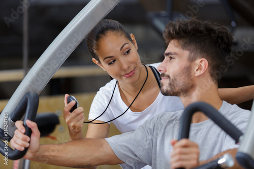 female gym trainer holding timer inspecting client