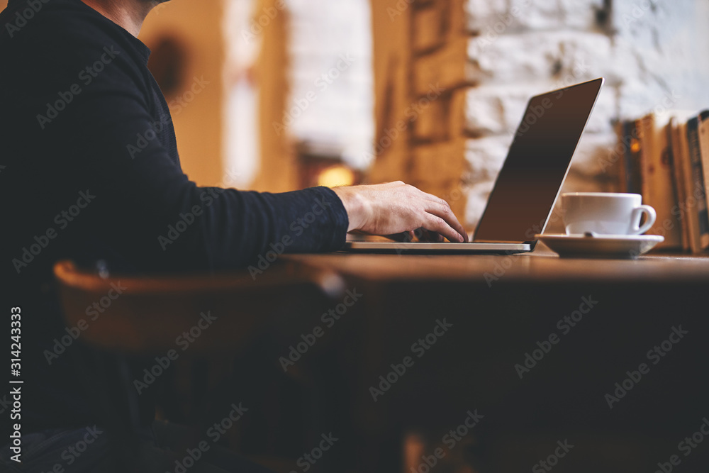 Man working on his laptop on a bar chair in a cafe by the window Man working on his laptop on a bar chair in a cafe by the window