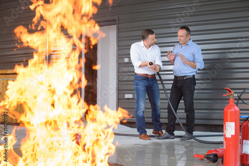 Canvas Print men and fire-extinguisher on flame background