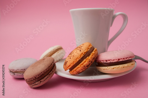 Closeup of french macarons and cup of coffee on pink background