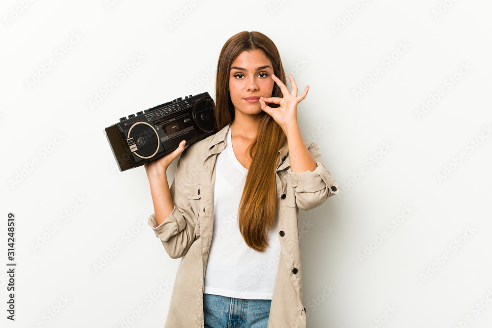 Young caucasian woman holding a guetto blaster with fingers on lips keeping a secret. Young caucasian woman holding a guetto blaster with fingers on lips keeping a secret.