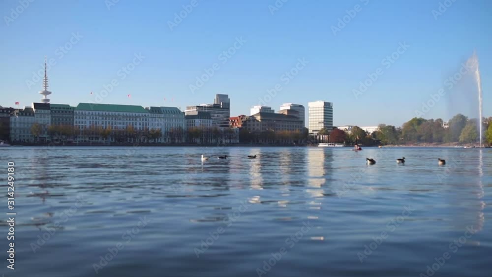 low angle view of Alster lake in Hamburg, Germany on sunny summer day against waterfront buildings and blue sky low angle view of Alster lake in Hamburg, Germany on sunny summer day against waterfront buildings and blue sky