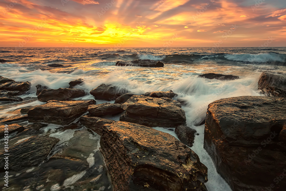 The stunning seascape with the colorful sky and first rays at the rocky coastline of the Black Sea