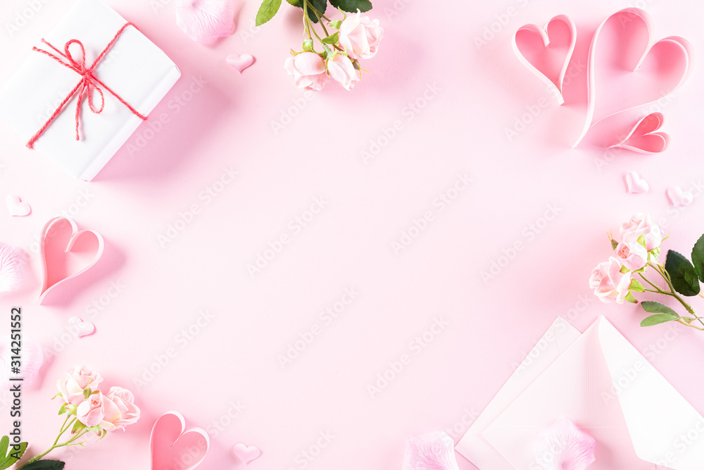 Pink paper hearts with gift box and roses on Light pink pastel paper background. Love and Valentine's day concept.