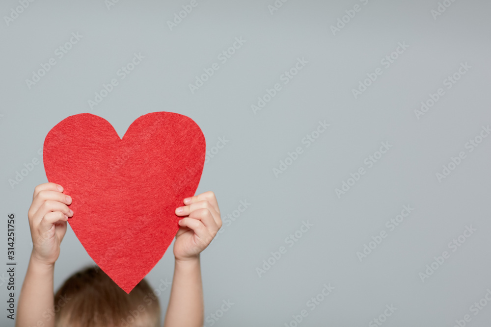 Little Boy hiding himself behind a red heart.Valentines Day concept. Little Boy hiding himself behind a red heart.Valentines Day concept.