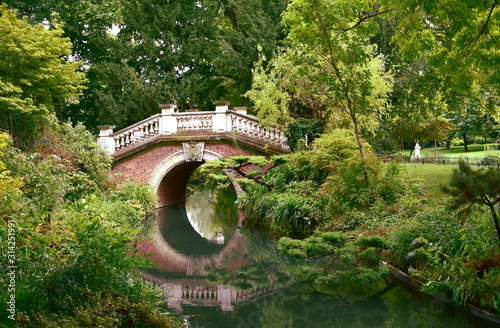 Bridge and river with water reflections in Parc Monceau. Paris, France.