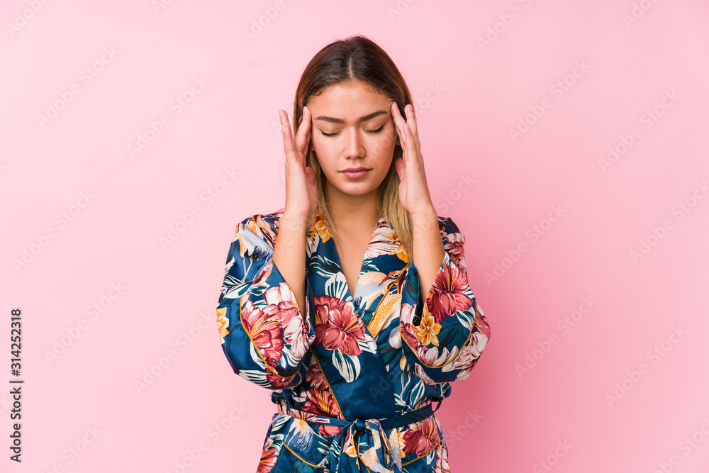 Young caucasian woman wearing pajamas touching temples and having headache. Young caucasian woman wearing pajamas touching temples and having headache.