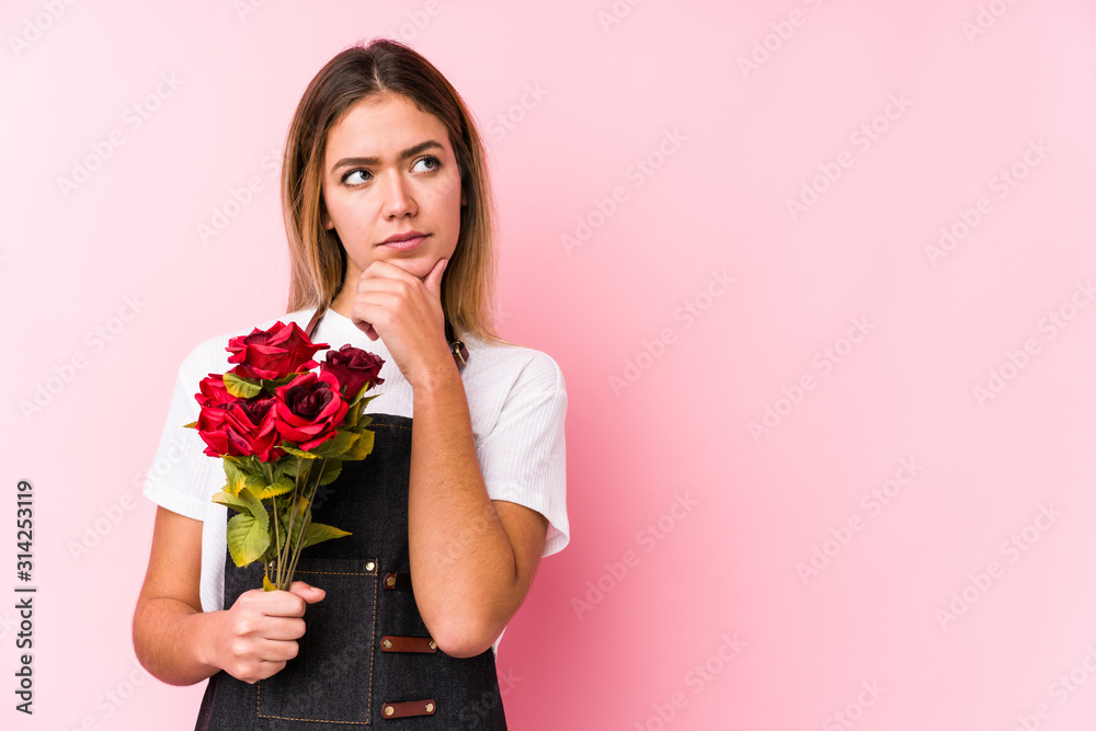 Young caucasian woman holding a roses isolated looking sideways with doubtful and skeptical expression. Young caucasian woman holding a roses isolated looking sideways with doubtful and skeptical expression.