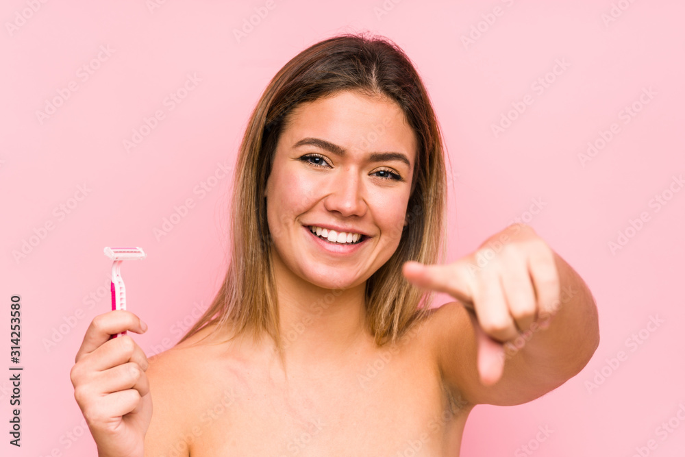 Young caucasian woman holding a razor blade isolated Young caucasian woman holding a hairbrush isolated cheerful smiles pointing to front.< mixto > Young caucasian woman holding a razor blade isolated Young caucasian woman holding a hairbrush isolated cheerful smiles pointing to front.< mixto >