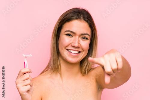Young caucasian woman holding a razor blade isolated Young caucasian woman holding a hairbrush isolated cheerful smiles pointing to front.< mixto >