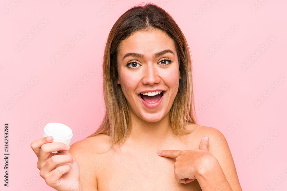 Young caucasian woman holding a moisturizer isolated surprised pointing at himself, smiling broadly. Young caucasian woman holding a moisturizer isolated surprised pointing at himself, smiling broadly.