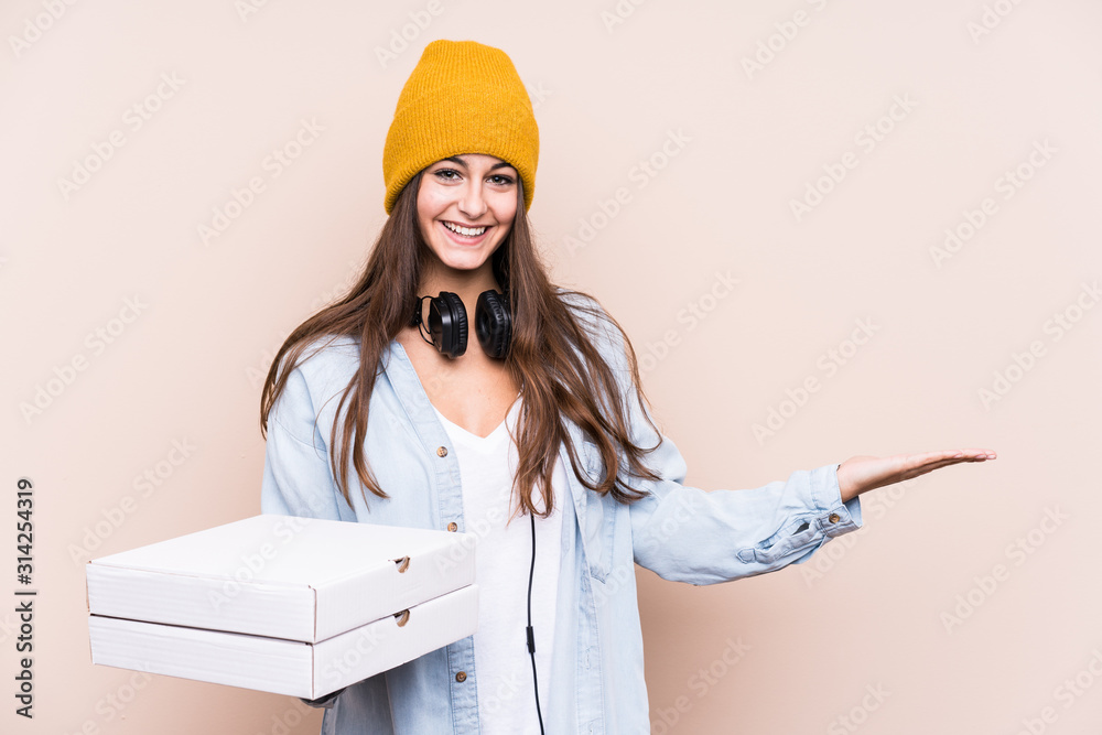 Young caucasian woman holding pizzas isolated showing a copy space on a palm and holding another hand on waist. Young caucasian woman holding pizzas isolated showing a copy space on a palm and holding another hand on waist.