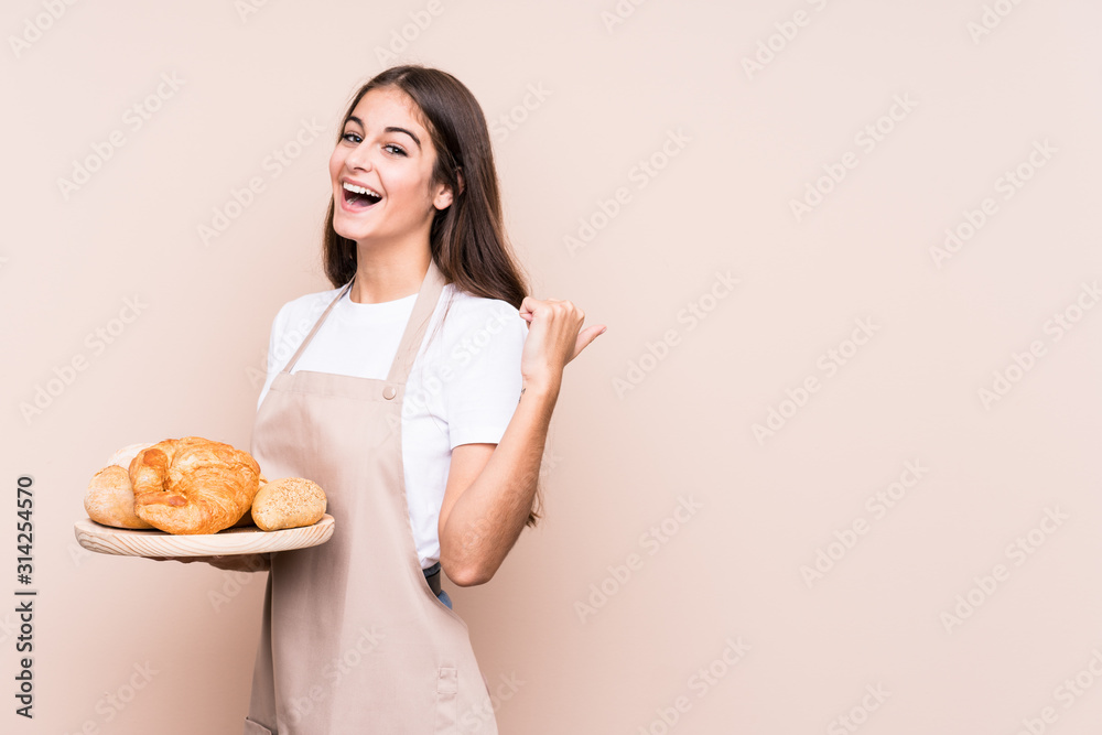 Young caucasian baker woman isolated points with thumb finger away, laughing and carefree. Young caucasian baker woman isolated points with thumb finger away, laughing and carefree.