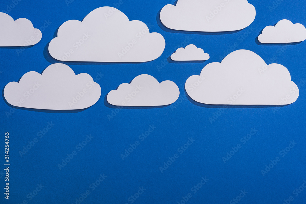 top view of white paper cut clouds on blue background top view of white paper cut clouds on blue background