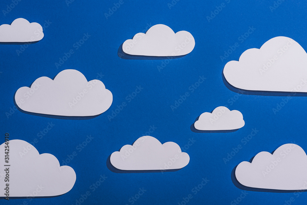 top view of white paper cut clouds on blue background