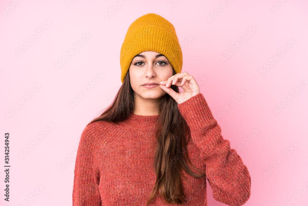 Young caucasian woman wearing a wool cap with fingers on lips keeping a secret. Young caucasian woman wearing a wool cap with fingers on lips keeping a secret.