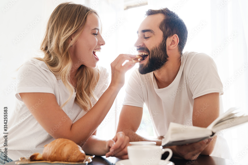 Happy beautiful young couple having breakfast at the kitchen table Happy beautiful young couple having breakfast at the kitchen table