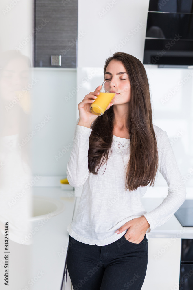 Portrait of happy smiling woman drinking fresh orange juice in the kitchen Portrait of happy smiling woman drinking fresh orange juice in the kitchen