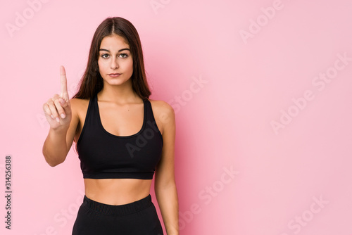 Young caucasian fitness woman doing sport isolated showing number one with finger. © Asier