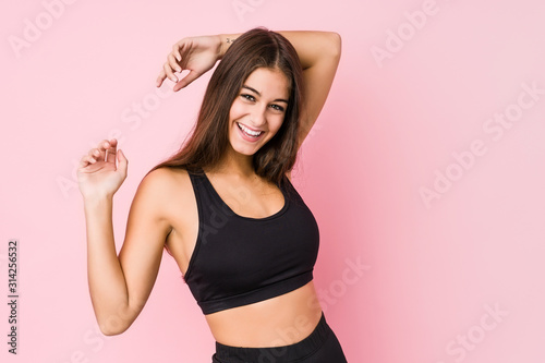 Young caucasian fitness woman doing sport isolated stretching arms, relaxed position.