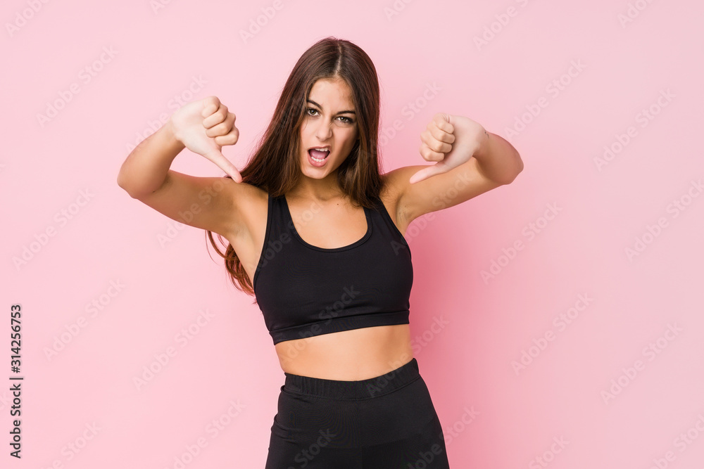 Young caucasian fitness woman doing sport isolated showing thumb down and expressing dislike.