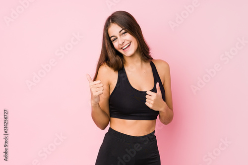 Young caucasian fitness woman doing sport isolated raising both thumbs up  smiling and confident.