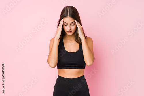 Young caucasian fitness woman doing sport isolated touching temples and having headache.