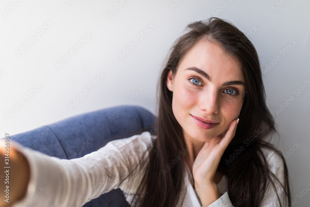 Portrait of girl taking a self-portrait with her smartphone at home. Portrait of girl taking a self-portrait with her smartphone at home.