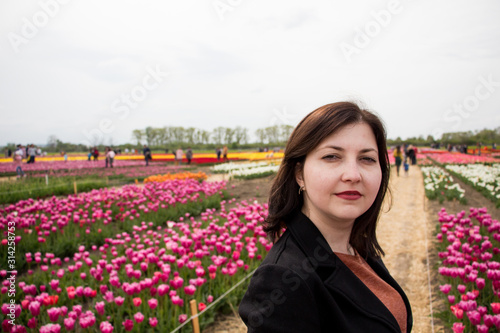 Beautiful brunette woman with tulips in field of flowers