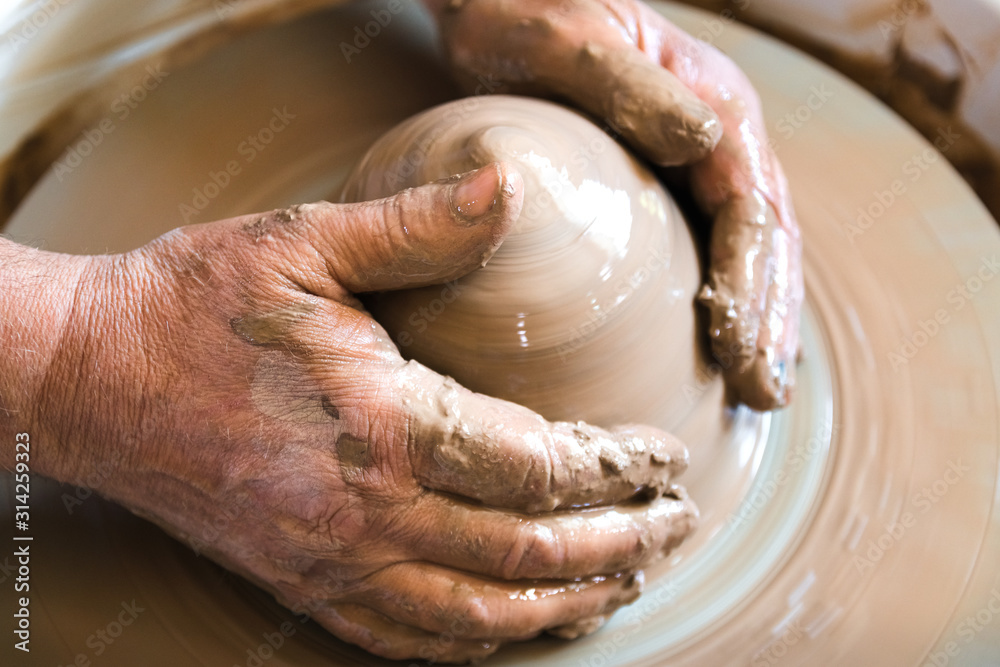 Portrait of craftsman working with clay in pottery workshop. Small business concept.