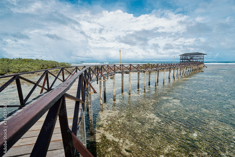 Beautiful landscape. Sunny day on seashore. Wooden bridge on Cloud 9 beach, Siargao Island Philippines.