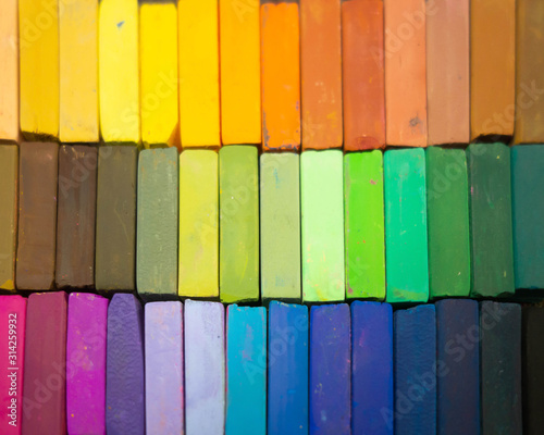 Used colorful pastel chalks in geometrical order. Artist supplies and accessories. Abstract horizontal background. Rainbow colors.