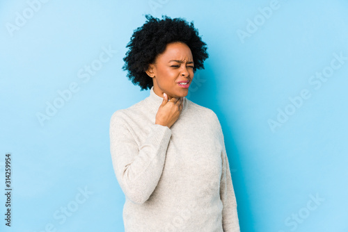 Middle aged african american woman against a blue background isolated suffers pain in throat due a virus or infection. photo