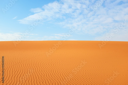 Desert summer background of bright orange desert sand and clear blue sky