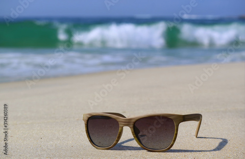 Sunglasses on the beach with blurry splashing waves in background