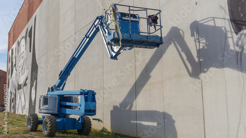 Slika na platnu Lift buckets or telescopic boom near empty factory wall.